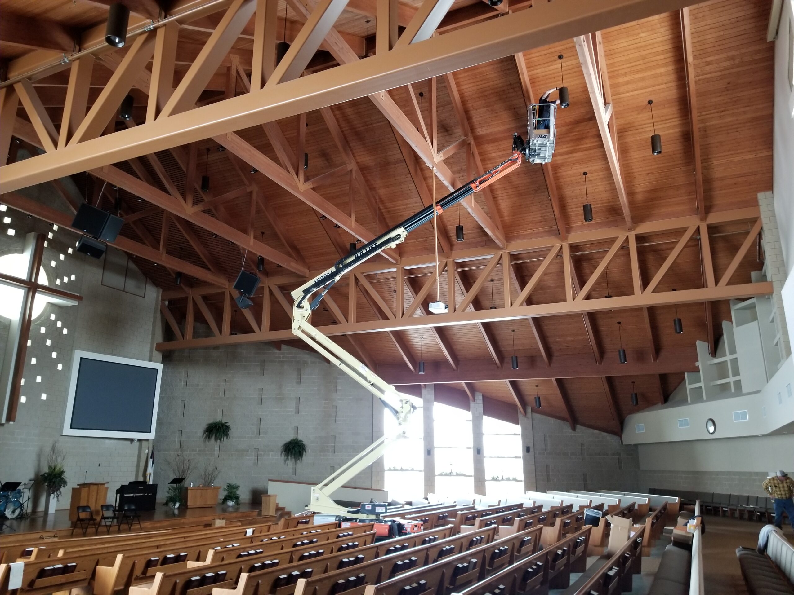 Jensen Electric Employee working on ceiling lights at a local church job site.